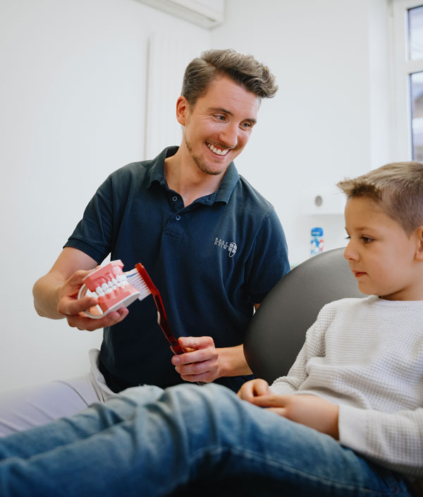 Kinderzahnarzt erklärt einem Kind die richtige Zahnpflege im MVZ Rage-Holm Bocholt